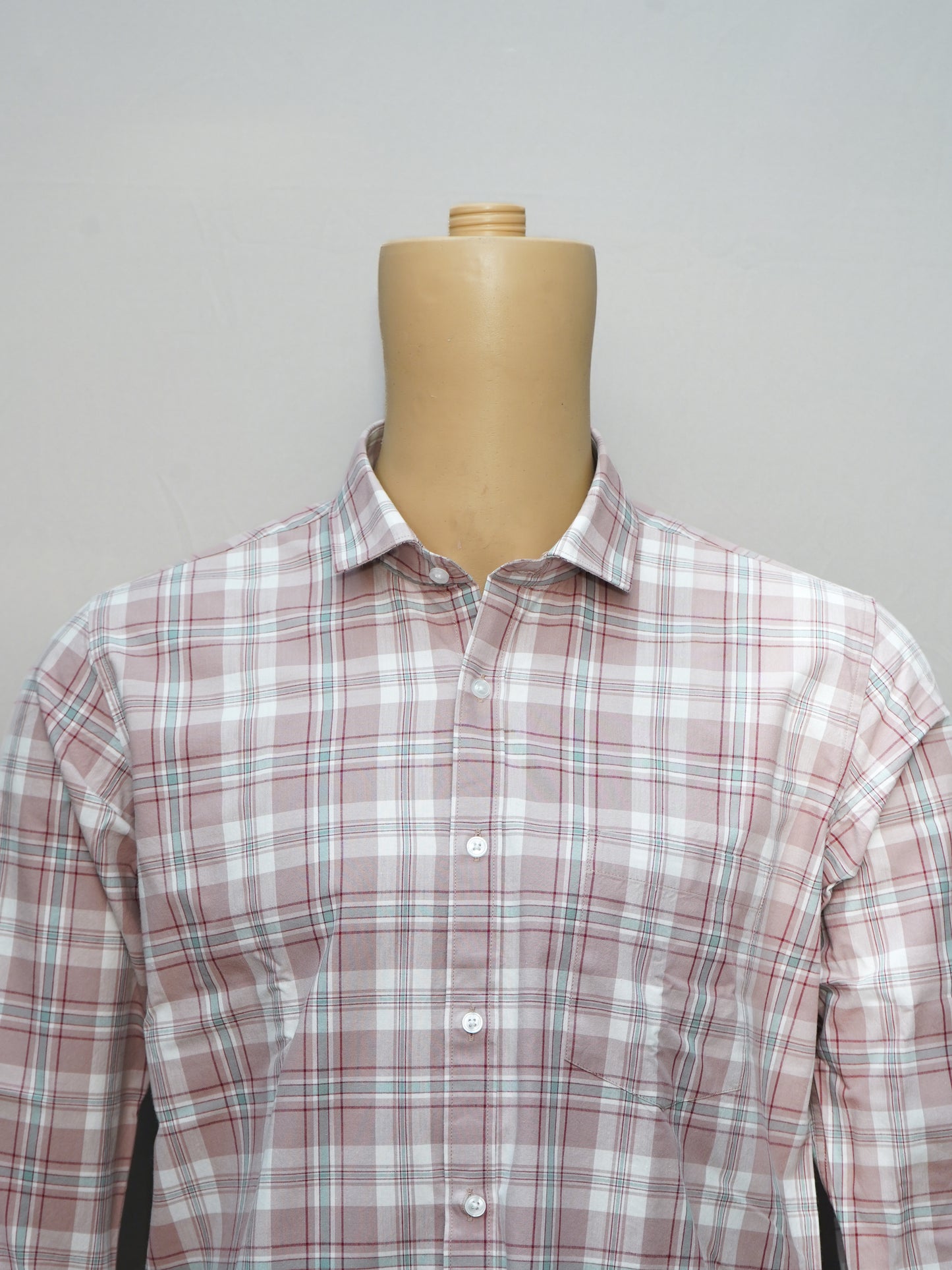Close-up of a blush pink check men's shirt, showcasing the intricate check pattern and button-down collar.
