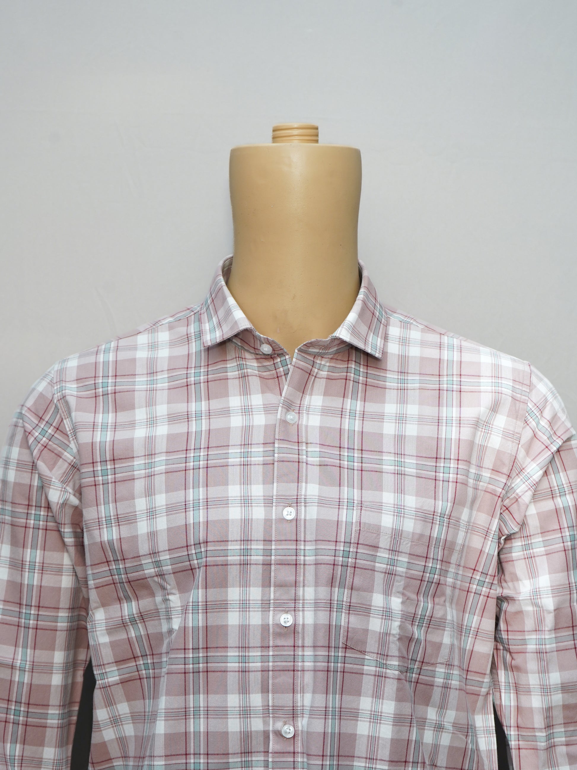 Close-up of a blush pink check men's shirt, showcasing the intricate check pattern and button-down collar.