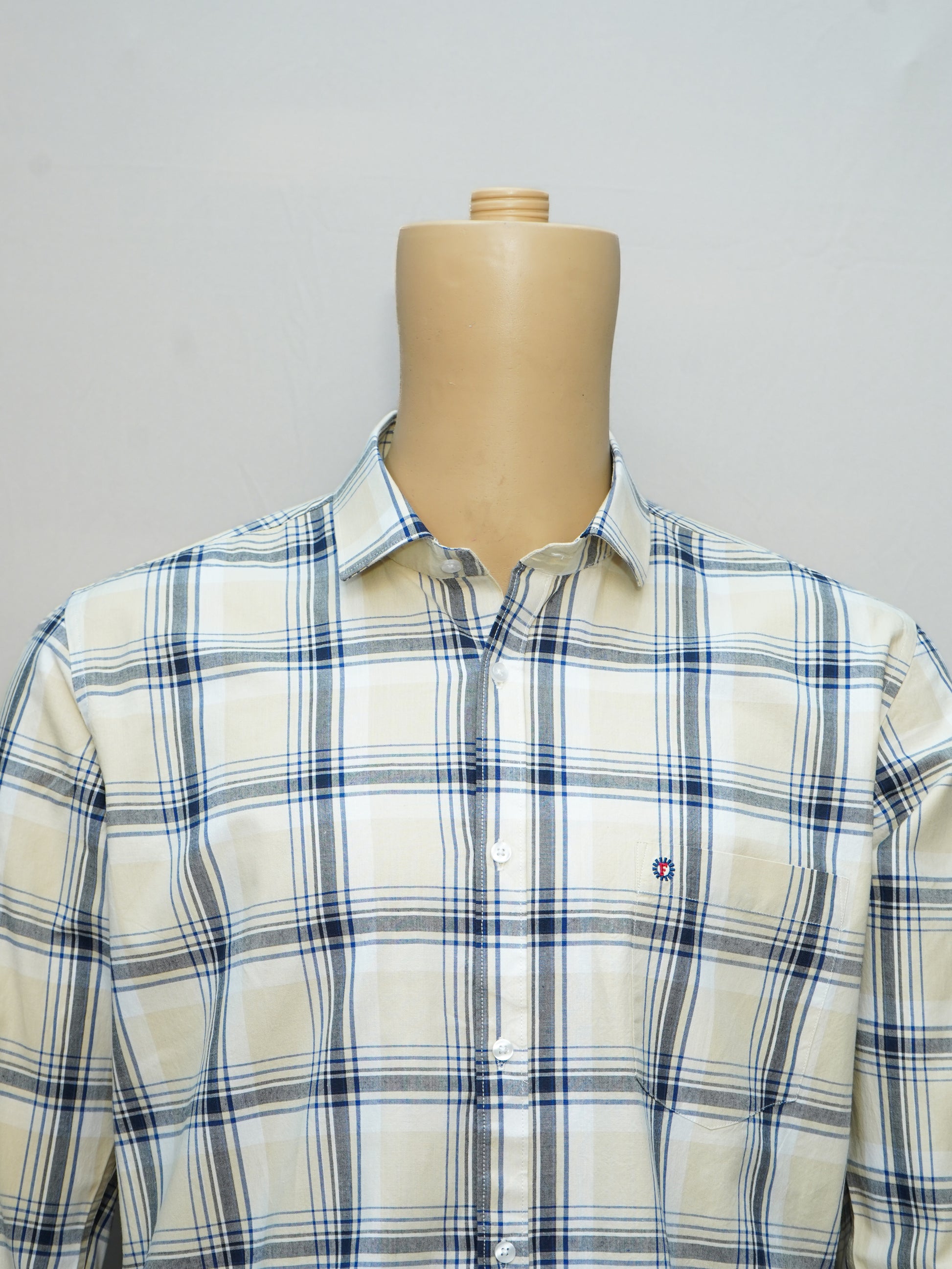 Close-up of a beige and blue check men's shirt, highlighting the fine checkered pattern and button-down collar.